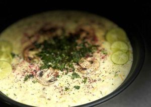 Turkish yogurt soup garnished with mushrooms and red peppers