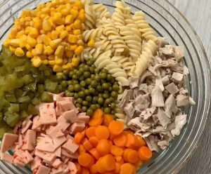 Creamy pasta salad with chicken, corn, peas, and pickles