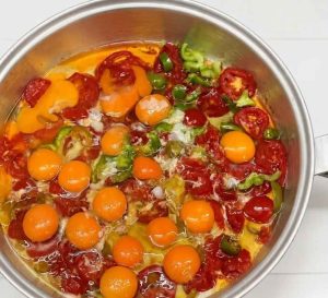 Traditional Persian Omelette cooking in a skillet with ripe tomatoes and eggs.