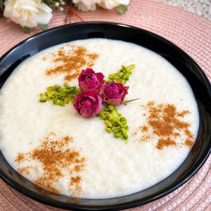 Homemade Shir Berenj served in a traditional bowl with dried rose petals and pistachios.