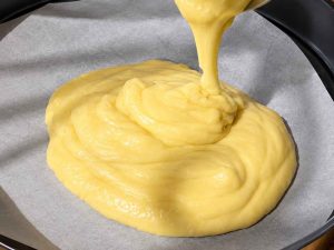 Pouring cake batter into a pan for Basbousa
