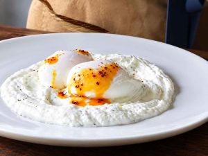  Spreading garlic yogurt on a plate for Turkish Eggs